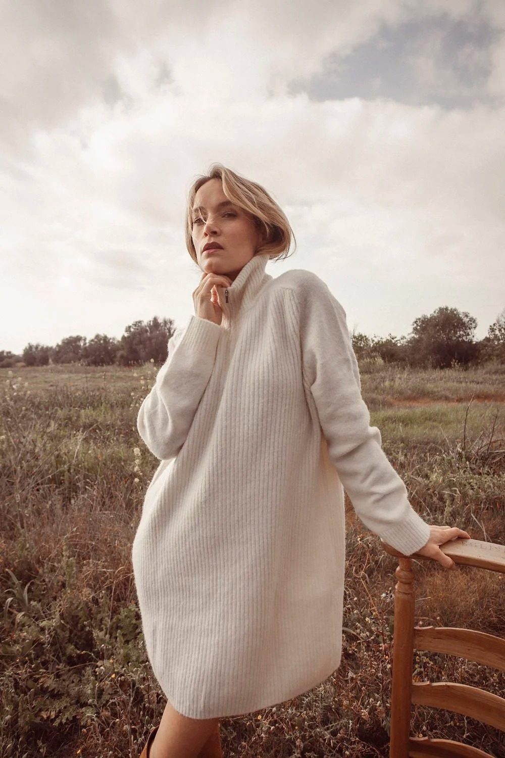 Model in cream knit dress in a winter field, FW25