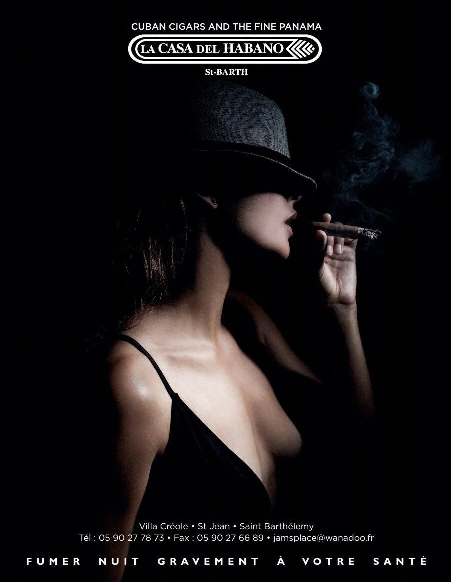 Print advertisement for La Casa del Habano, woman with cigar in low light, St-Barth