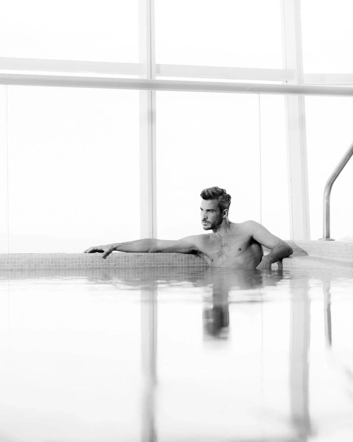 Man resting at the edge of an indoor pool, high-key black and white, St. Regis Mexico City